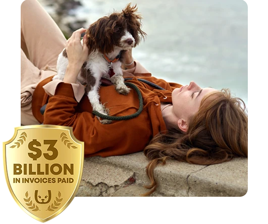 Woman laying on a seawall with her pet dog sitting on her. Trupanion $2 billion logo in the corner.