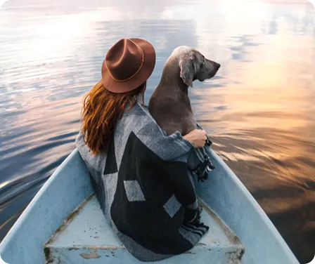 A pet owner in a boat with their dog looking to learn how much is pet insurance a month.